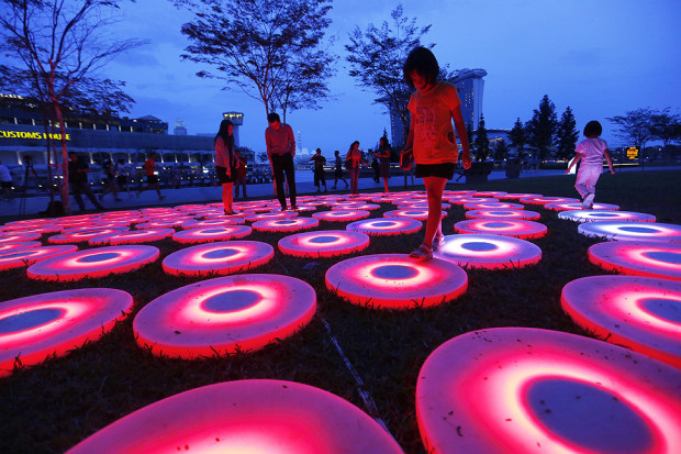 Visitors walk over light art installation titled 'The Pool' by Jen Lewin Studio during the i Light Marina Bay 2014 festival in Singapore.
